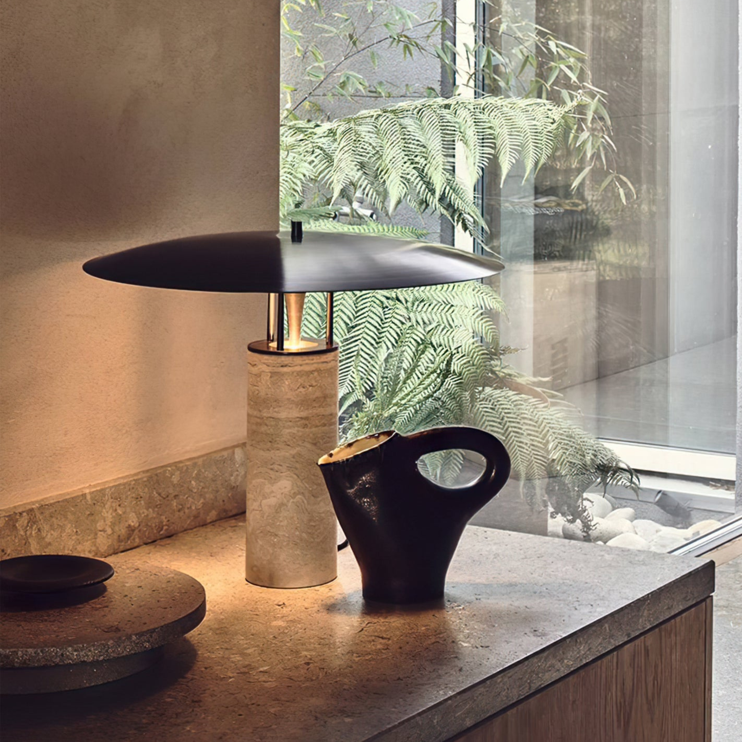 Elegant tabletop near a window with a bamboo lamp and a black ceramic teapot in natural light.