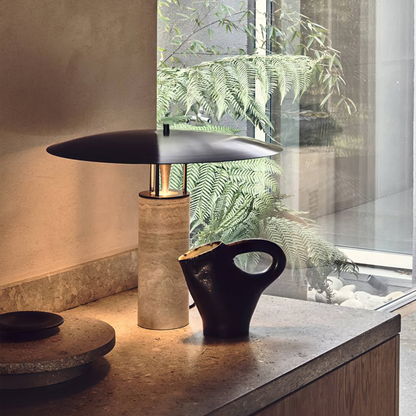 Elegant tabletop near a window with a bamboo lamp and a black ceramic teapot in natural light.