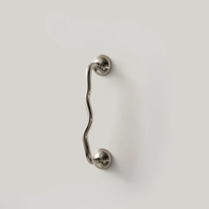 Shorter wavy stainless steel handle mounted on a minimal white surface