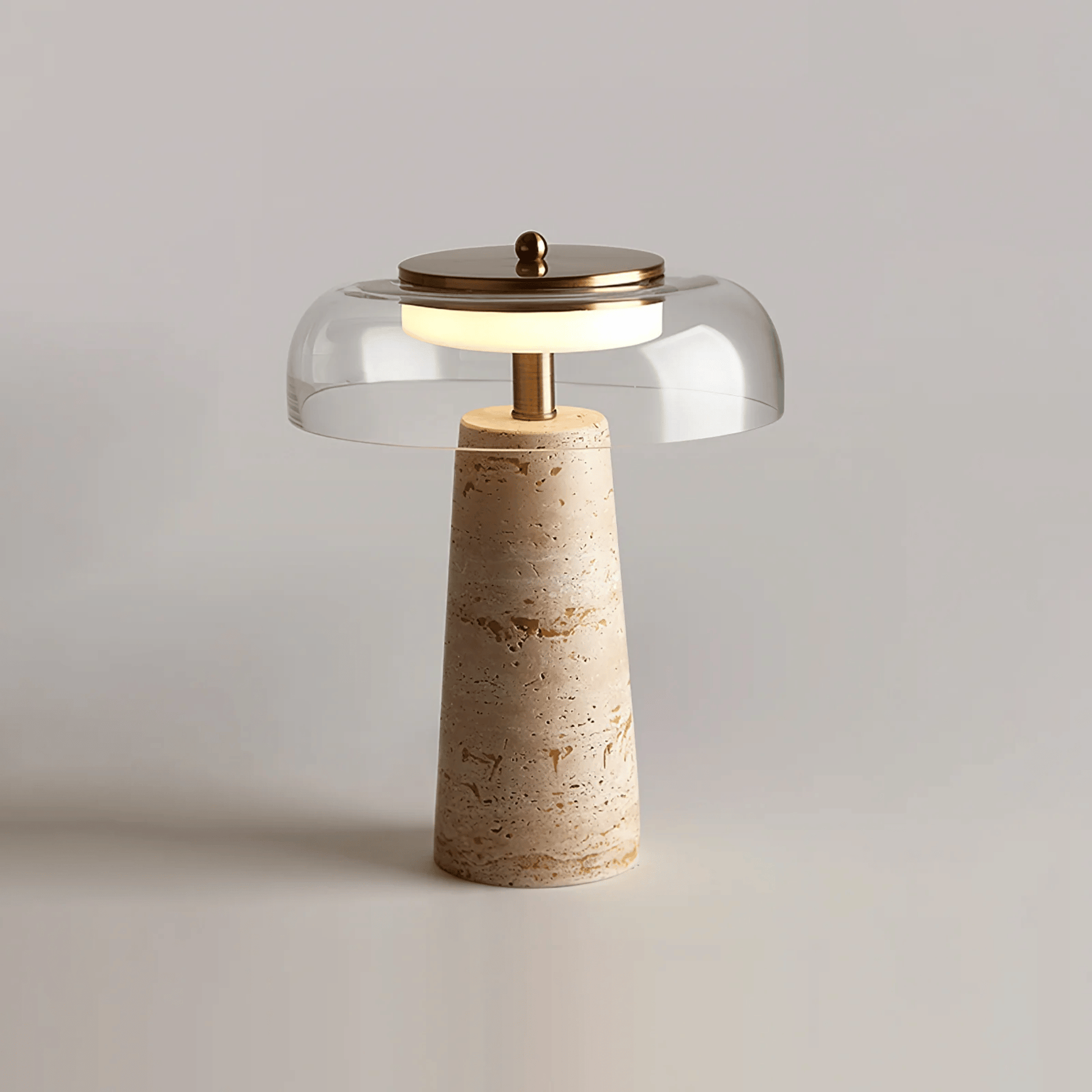 Table lamp with a beige stone base and clear glass shade on a light gray background