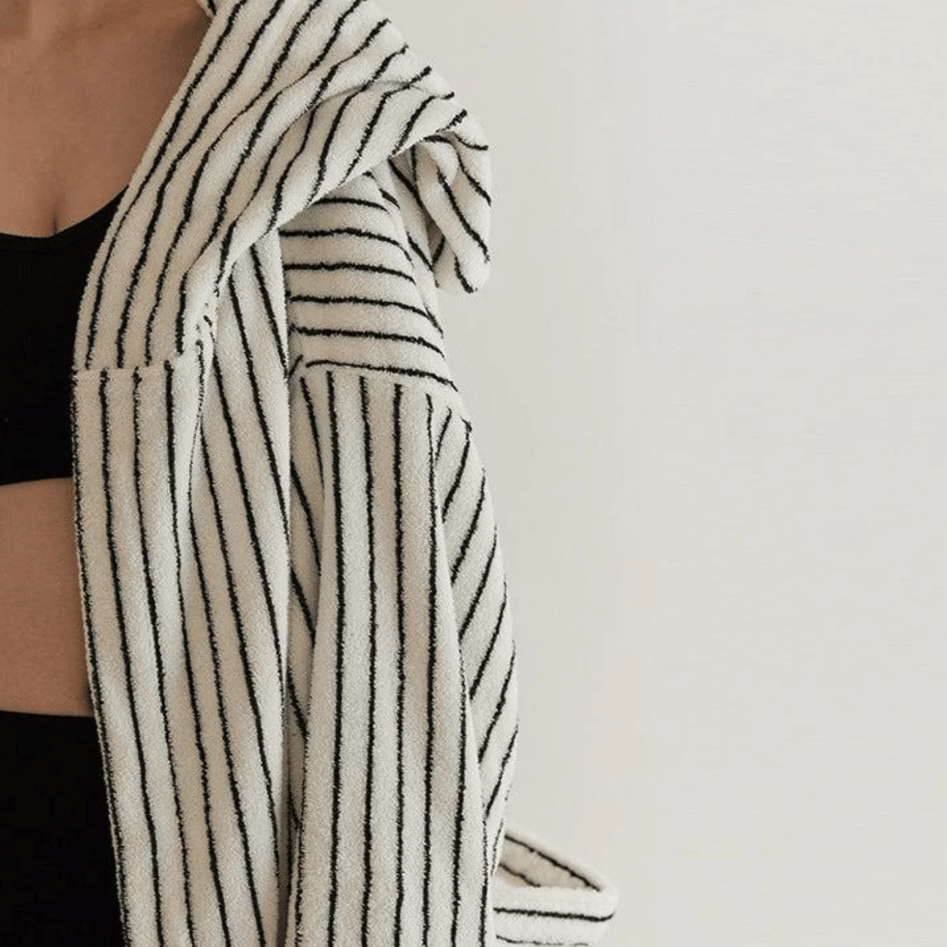 Person wearing a black and white striped robe against a plain background