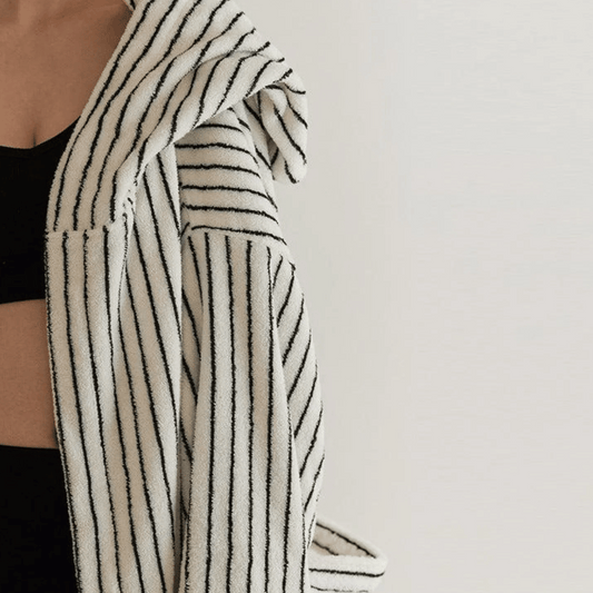 Person wearing a black and white striped robe against a plain background