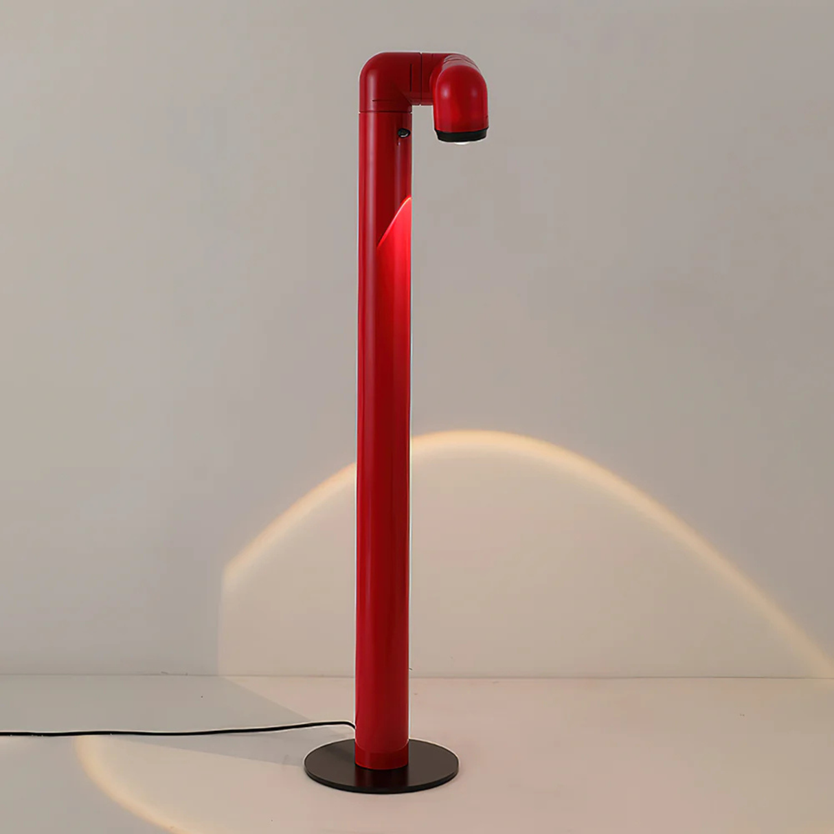 A red floor lamp standing in a room with soft light casting on the floor, creating a calm ambiance.
