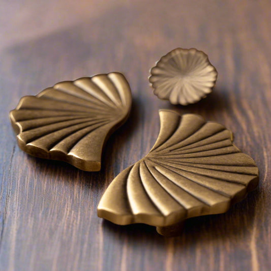 Brass shell-shaped knobs on a wooden surface.