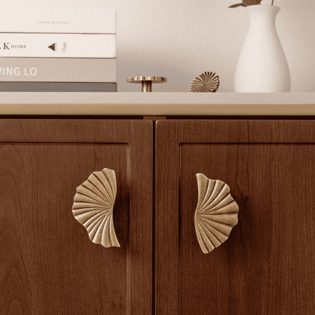 Wooden cabinet with shell-shaped handles on a neutral background