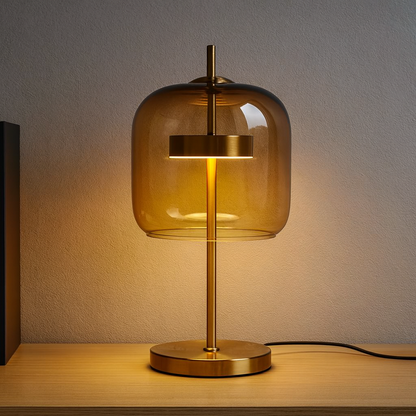 Gold table lamp with amber glass shade on a wooden surface.