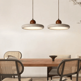 Dining area with wooden table and chairs under two pendant lights.