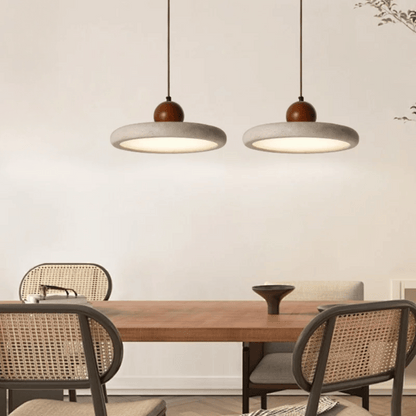Dining area with wooden table and chairs under two pendant lights.