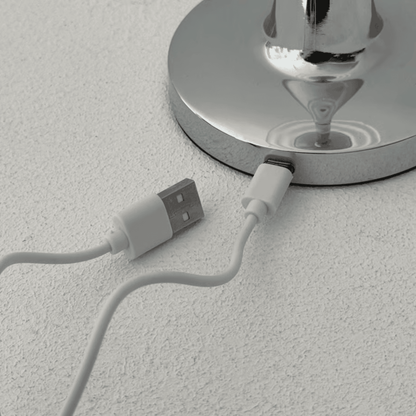 USB cable plugged into a metallic faucet on a textured surface