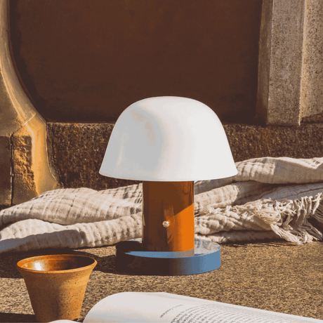 White lamp on a stone surface with a book and small plant