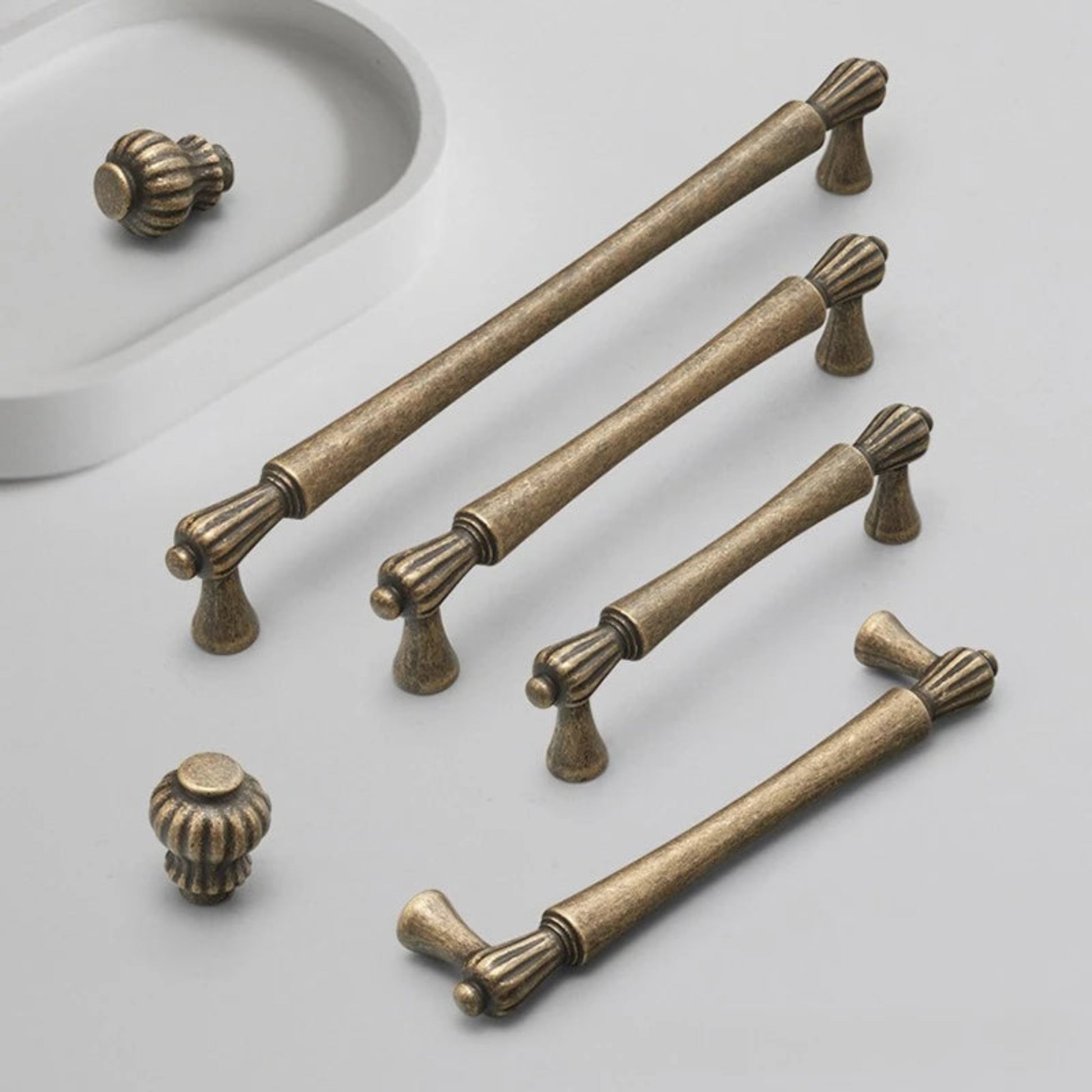 Set of bronze cabinet handles and knobs on a light gray background