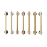 Set of gold cabinet handles with marble knobs on a white background