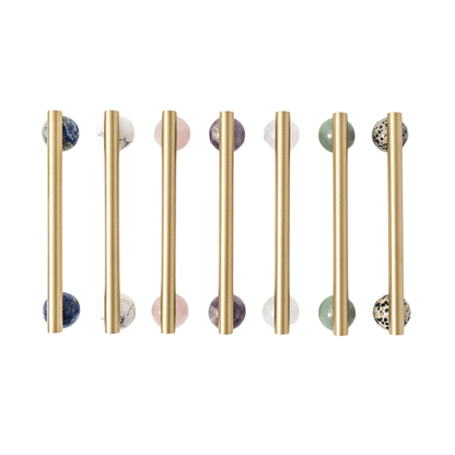 Set of gold cabinet handles with marble knobs on a white background