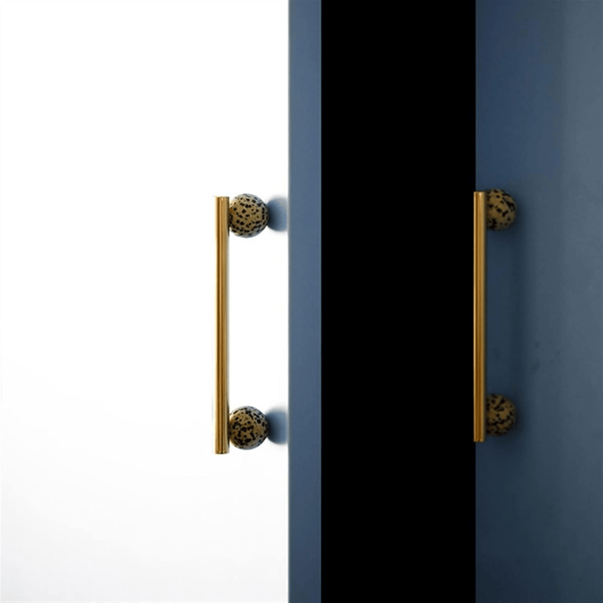 Pair of gold cabinet handles on a black and blue door