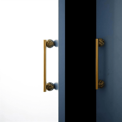 Pair of gold cabinet handles on a black and blue door