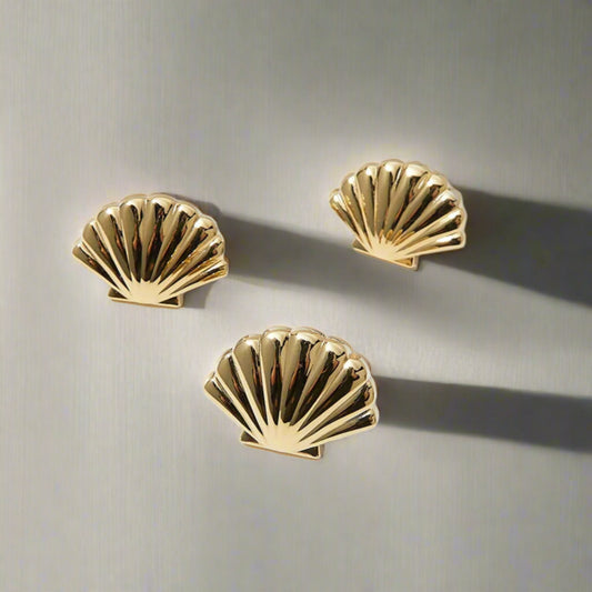 Three gold shell-shaped earrings on a white background