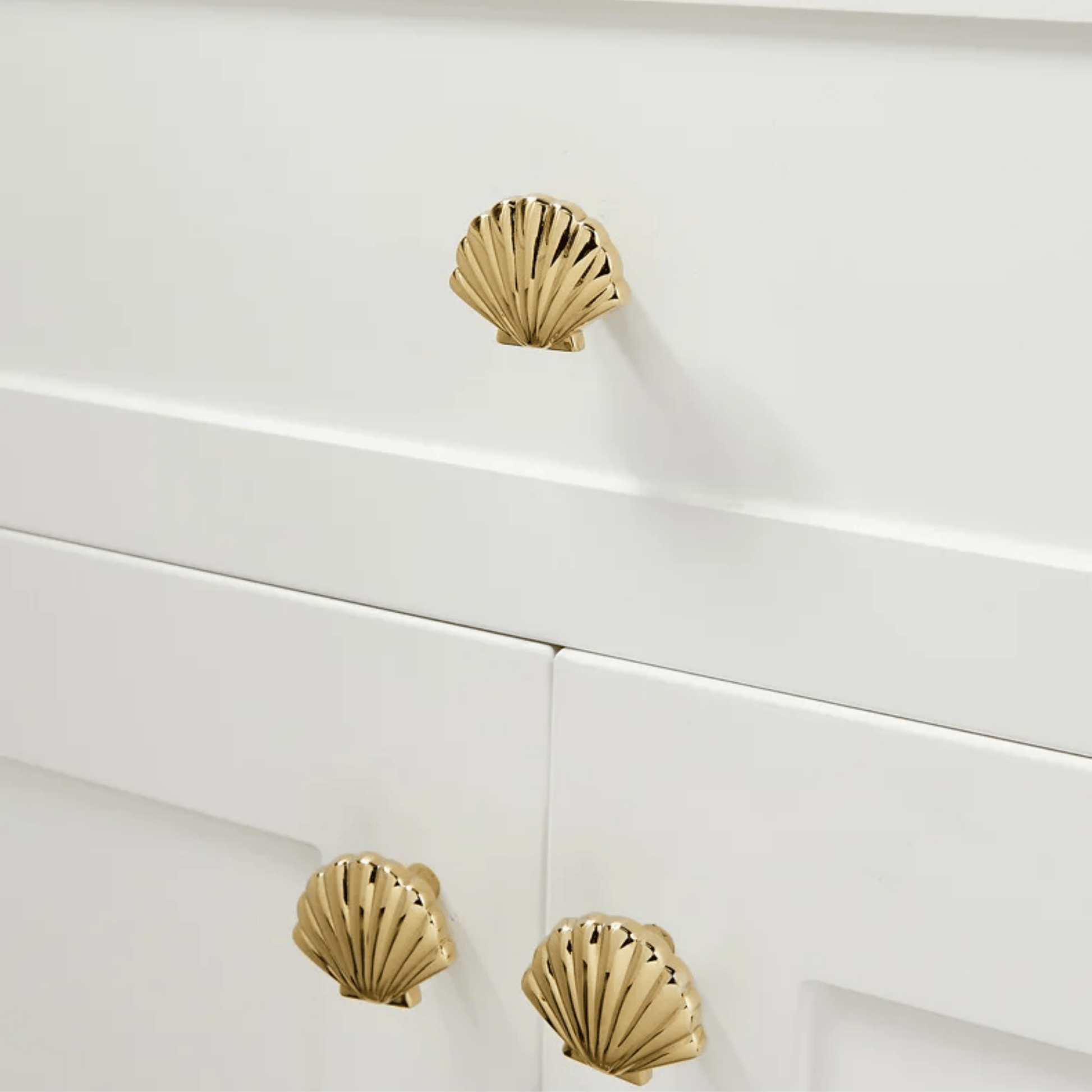Gold shell-shaped cabinet knobs on a white cabinet