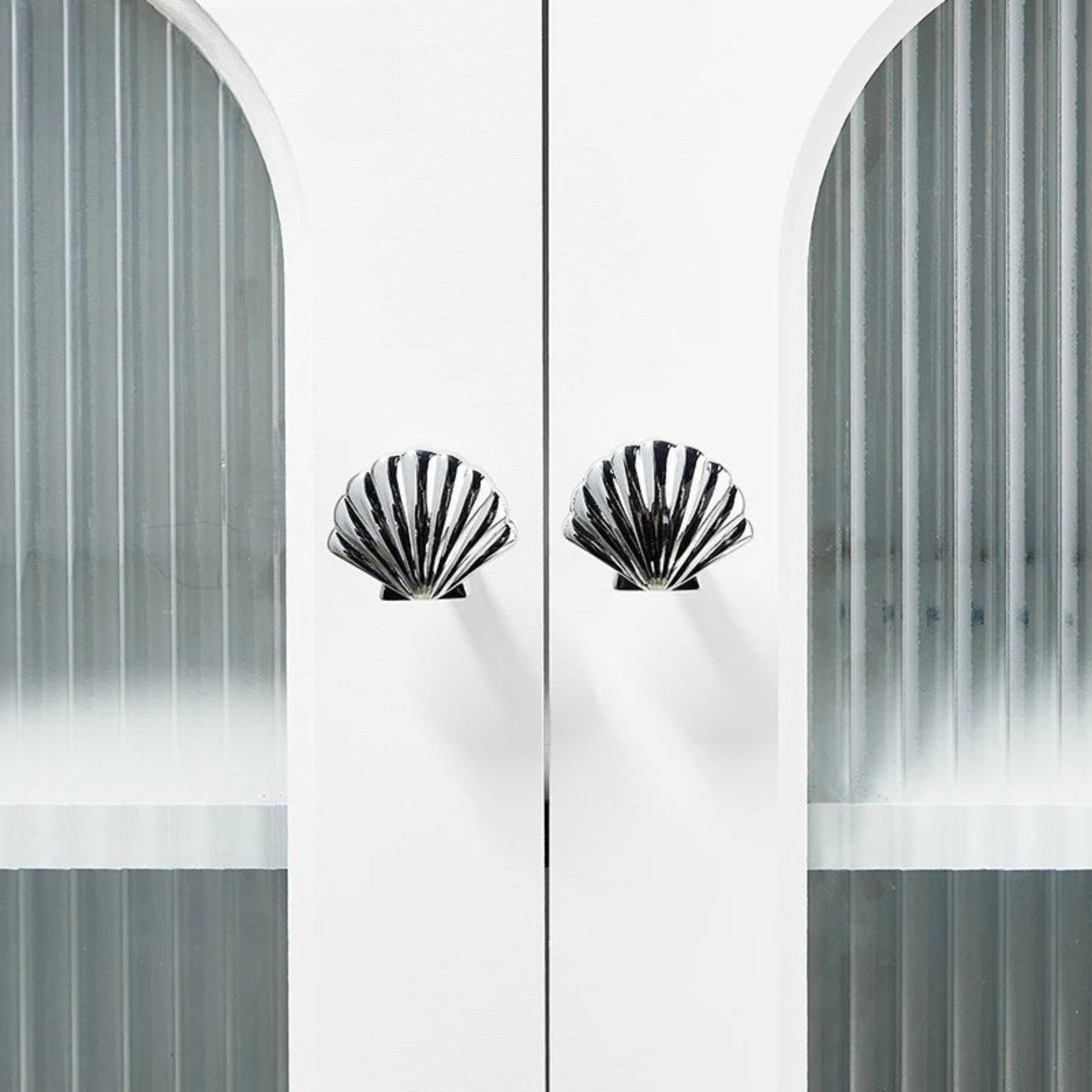 Decorative cabinet with shell-shaped handles against a white background
