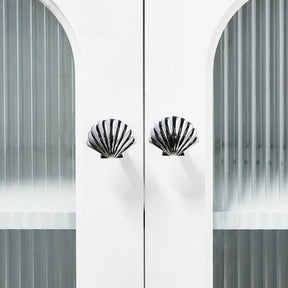 Decorative cabinet with shell-shaped handles against a white background
