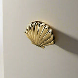 Gold shell-shaped door handle on a wooden door