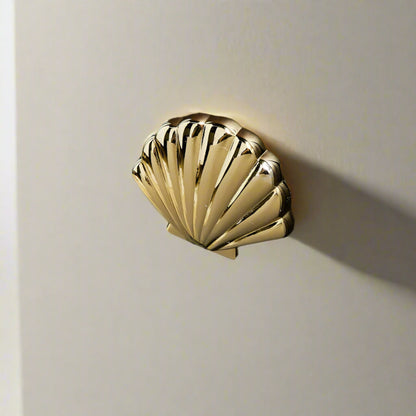 Gold shell-shaped door handle on a wooden door