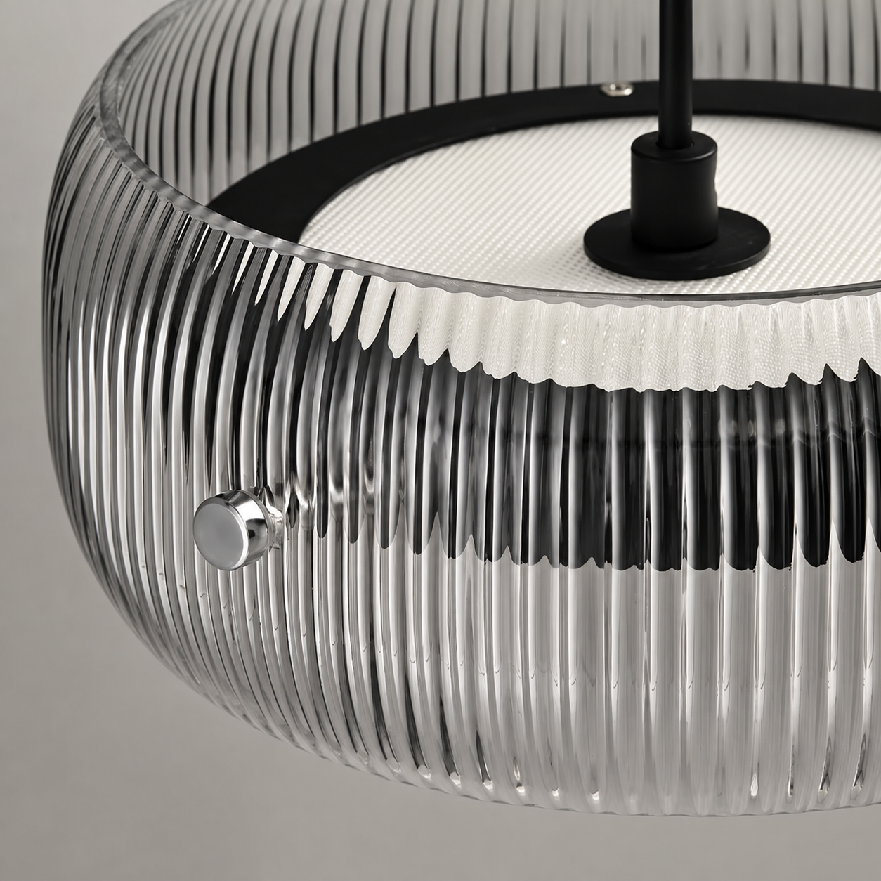Close-up of a modern pendant light with a ribbed clear glass shade, black top band and central rod, and a white inner ring.