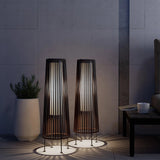 Two tall, cylindrical floor lamps with a modern design in a dimly lit room.