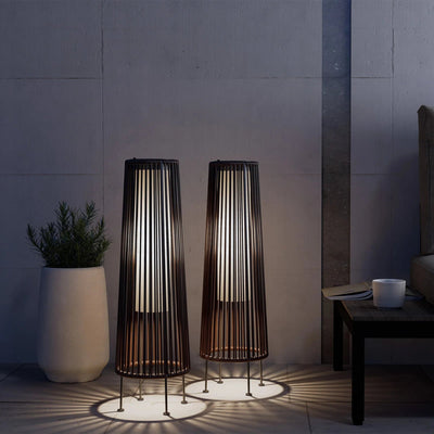 Two tall, cylindrical floor lamps with a modern design in a dimly lit room.