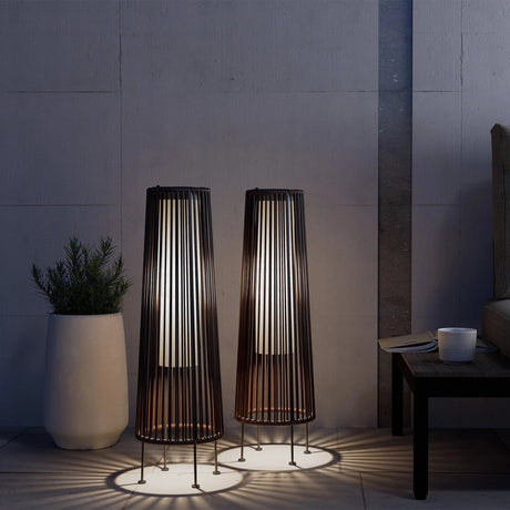 Two tall, cylindrical floor lamps with a modern design in a dimly lit room.