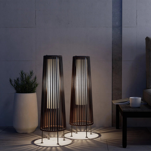 Two tall, cylindrical floor lamps with a modern design in a dimly lit room.