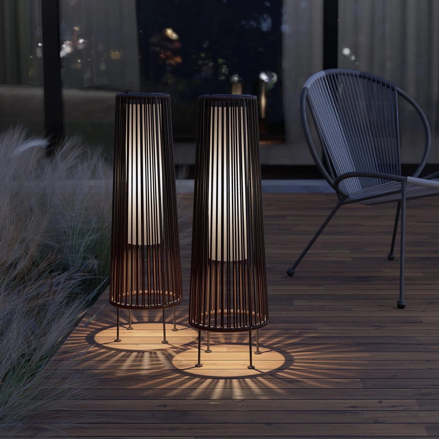 Two outdoor floor lamps casting shadows on a wooden deck at night.