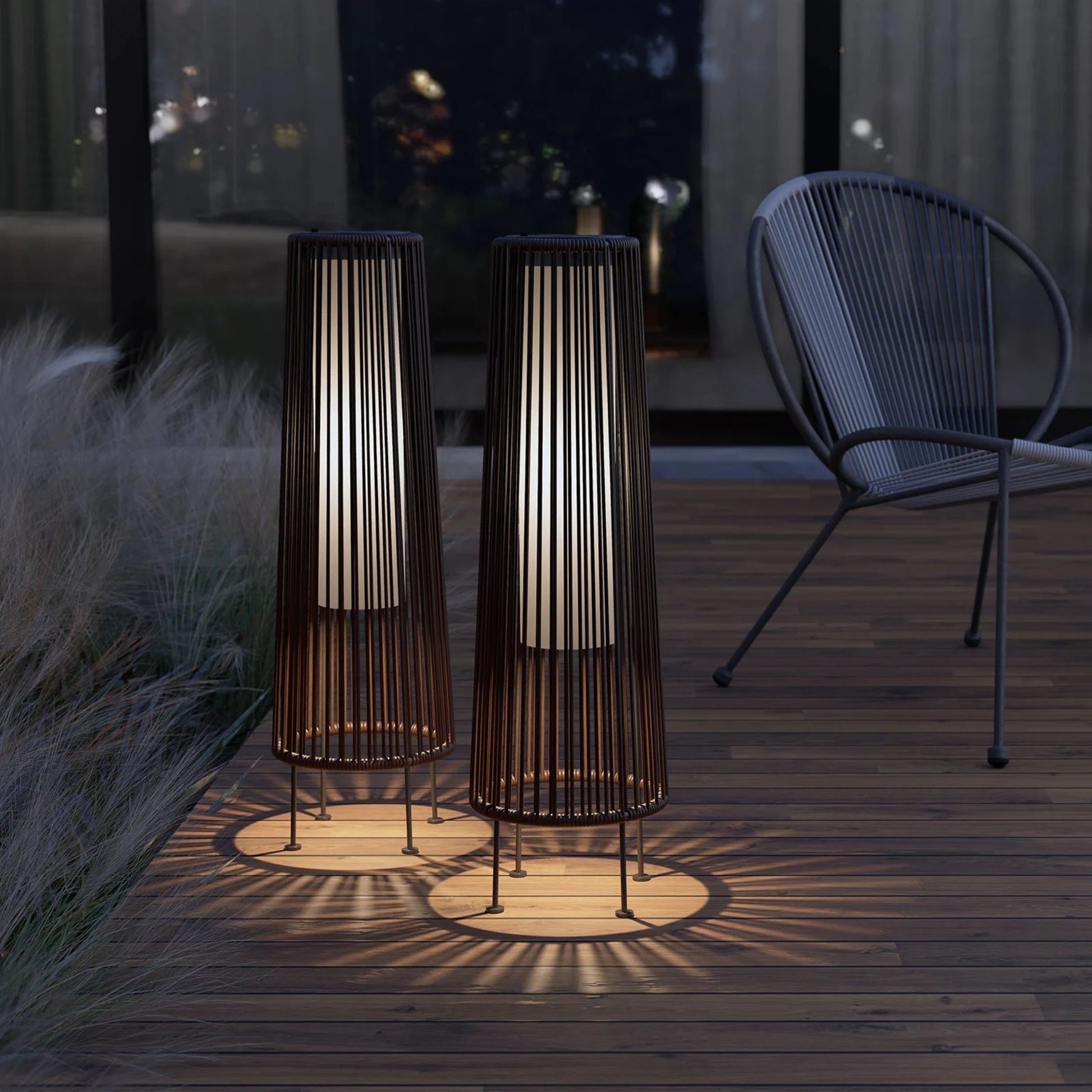 Two outdoor floor lamps casting shadows on a wooden deck at night.