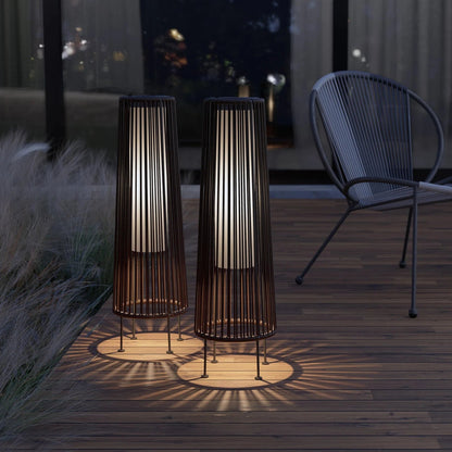 Two outdoor floor lamps casting shadows on a wooden deck at night.