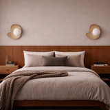 Neatly made bed with beige bedding and decorative pillows in a bedroom setting.