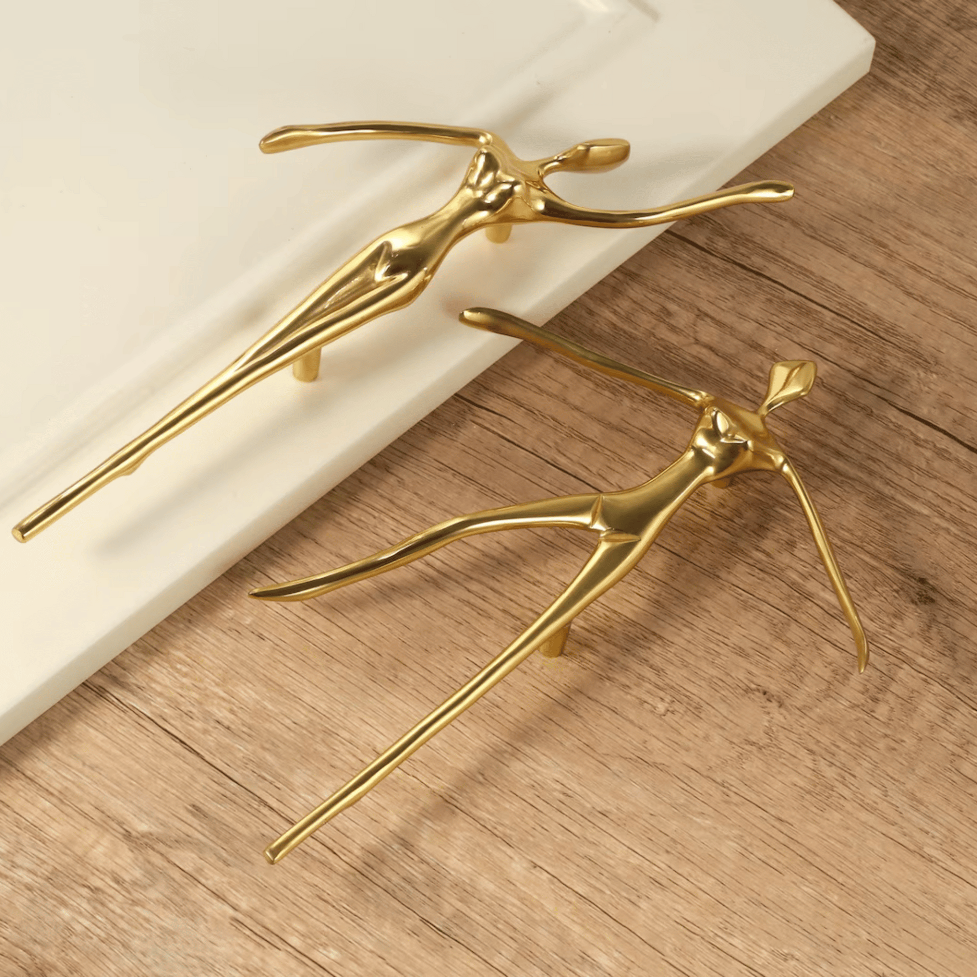 Two gold door handles on a wooden surface