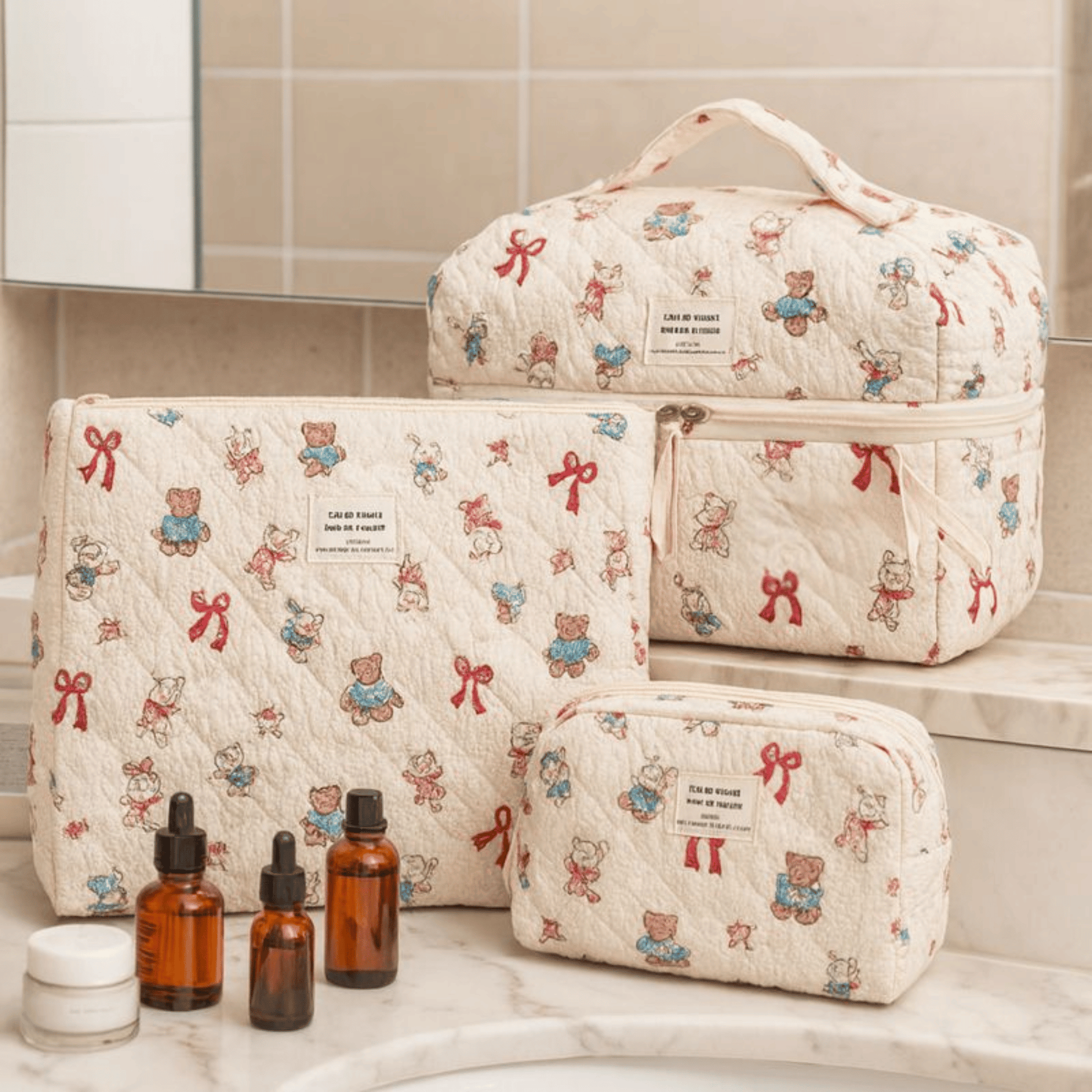 Set of quilted cosmetic bags with teddy bear and bow pattern on a bathroom counter.