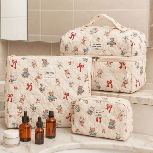 Set of quilted cosmetic bags with teddy bear and bow pattern on a bathroom counter.