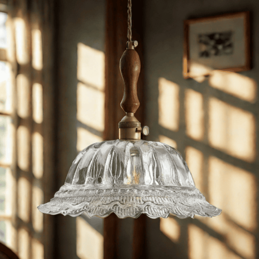 Vintage-style pendant light with clear glass shade and wooden fixture hanging in a room with sunlight filtering through.