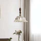 Glass pendant light fixture with wooden accent hanging above a table with flowers.