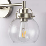 Wall-mounted light fixture with clear glass shade and metallic finish on a white background