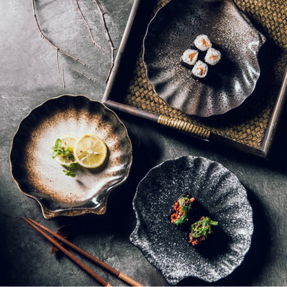 Three dark ceramic plates with food on a textured surface