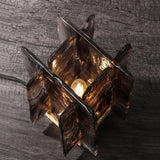 Glass table lamp with a textured design on a wooden surface and concrete wall background