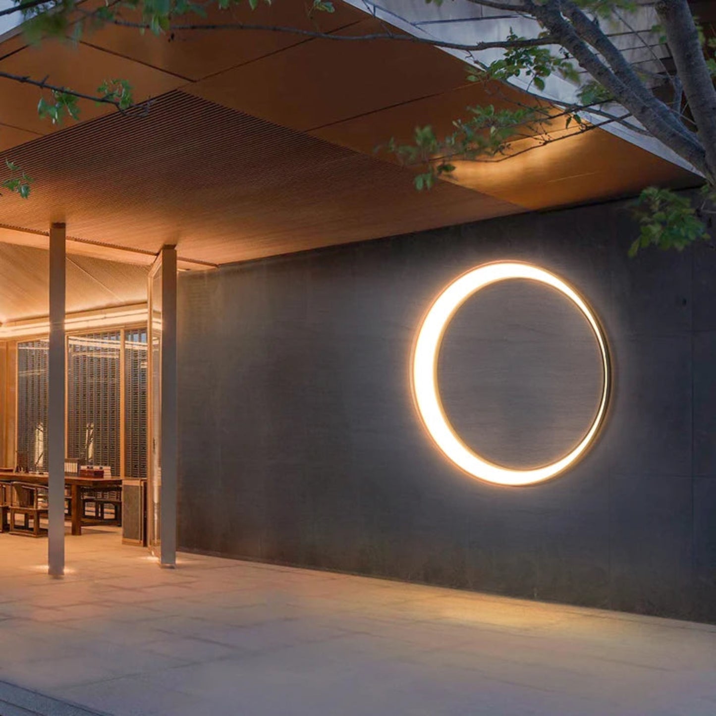 Modern outdoor setting with a circular light fixture on a dark wall.