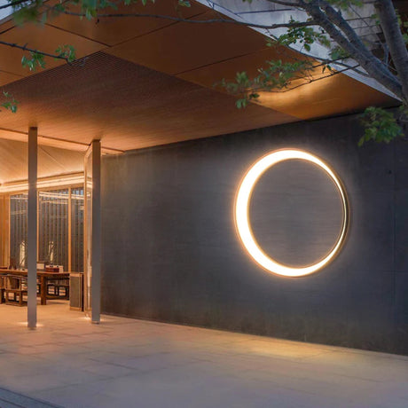 Modern outdoor setting with a circular light fixture on a dark wall.