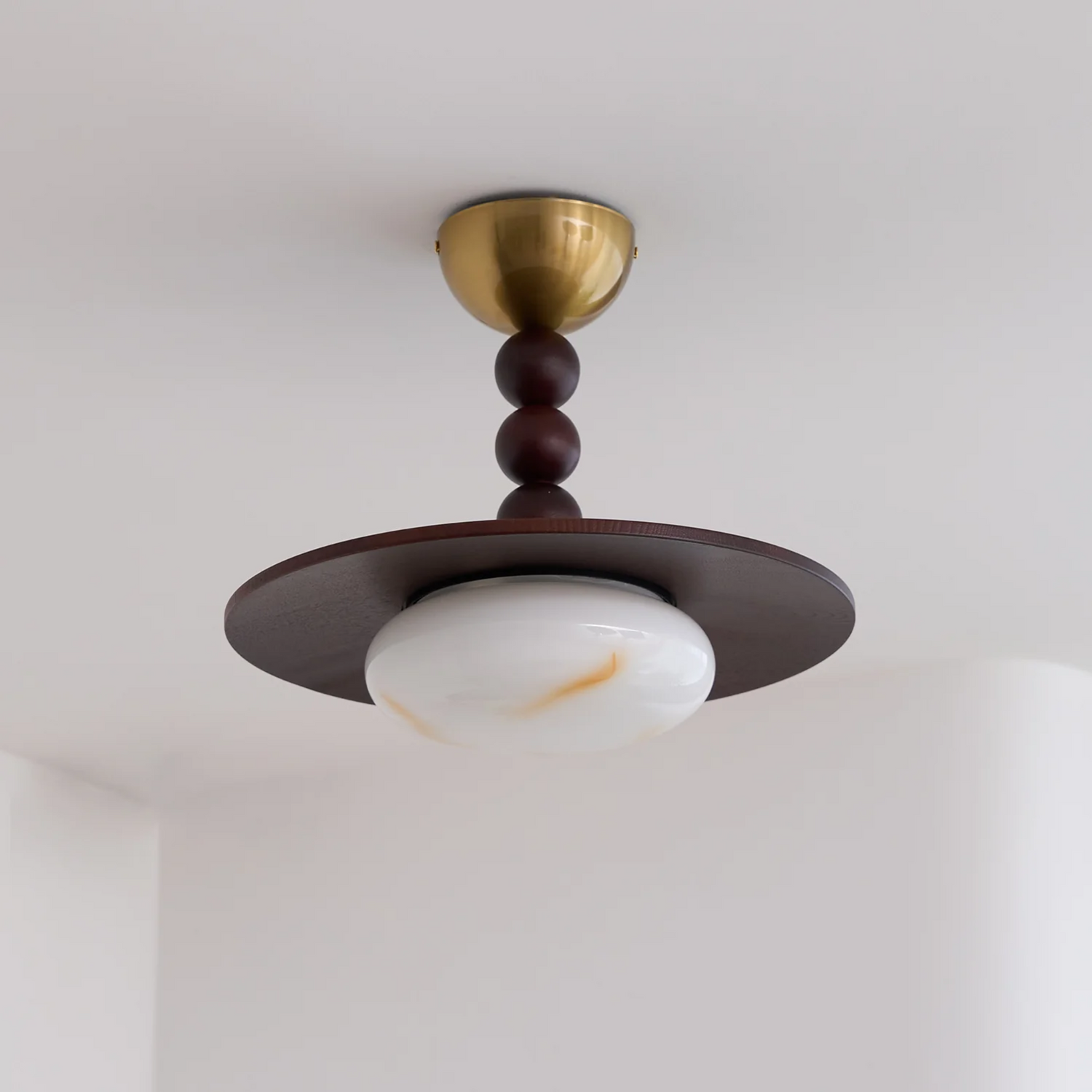 Ceiling light fixture with brass and wood design on a white ceiling