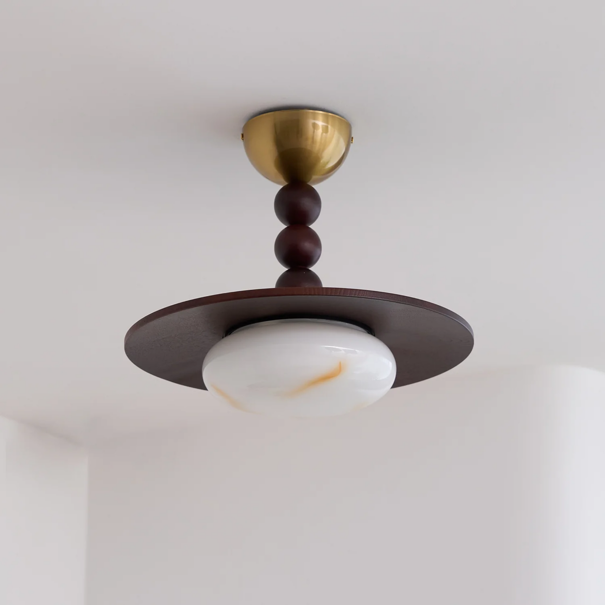 Ceiling light fixture with brass and wood design on a white ceiling