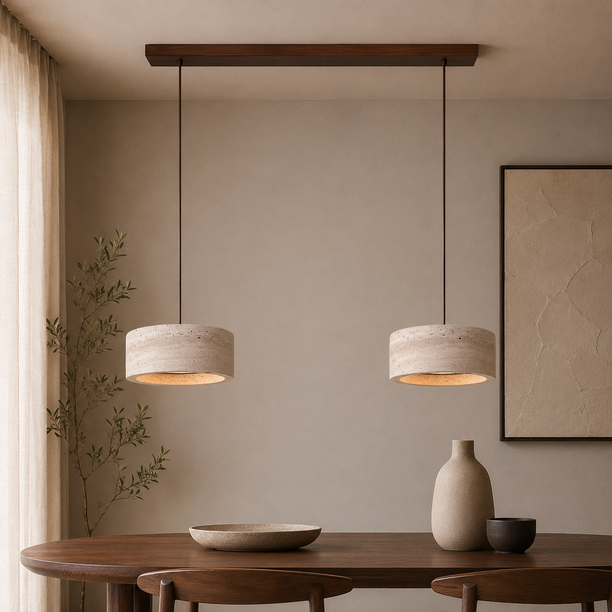 Two modern pendant lights with textured beige drum shades hang over a wooden dining table in a minimalist, warm-toned room with a beige wall and neutral decor.