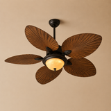 A five-blade ceiling fan with decorative wood-look blades and a warm glowing light fixture in a dark metal center, shown against a plain beige wall.