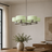 A modern six-light chandelier with pale mint green ribbed glass shades and a polished silver metal frame, hanging in a styled dining room above a wooden table.