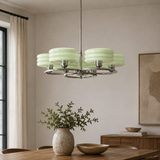 A modern six-light chandelier with pale mint green ribbed glass shades and a polished silver metal frame, hanging in a styled dining room above a wooden table.